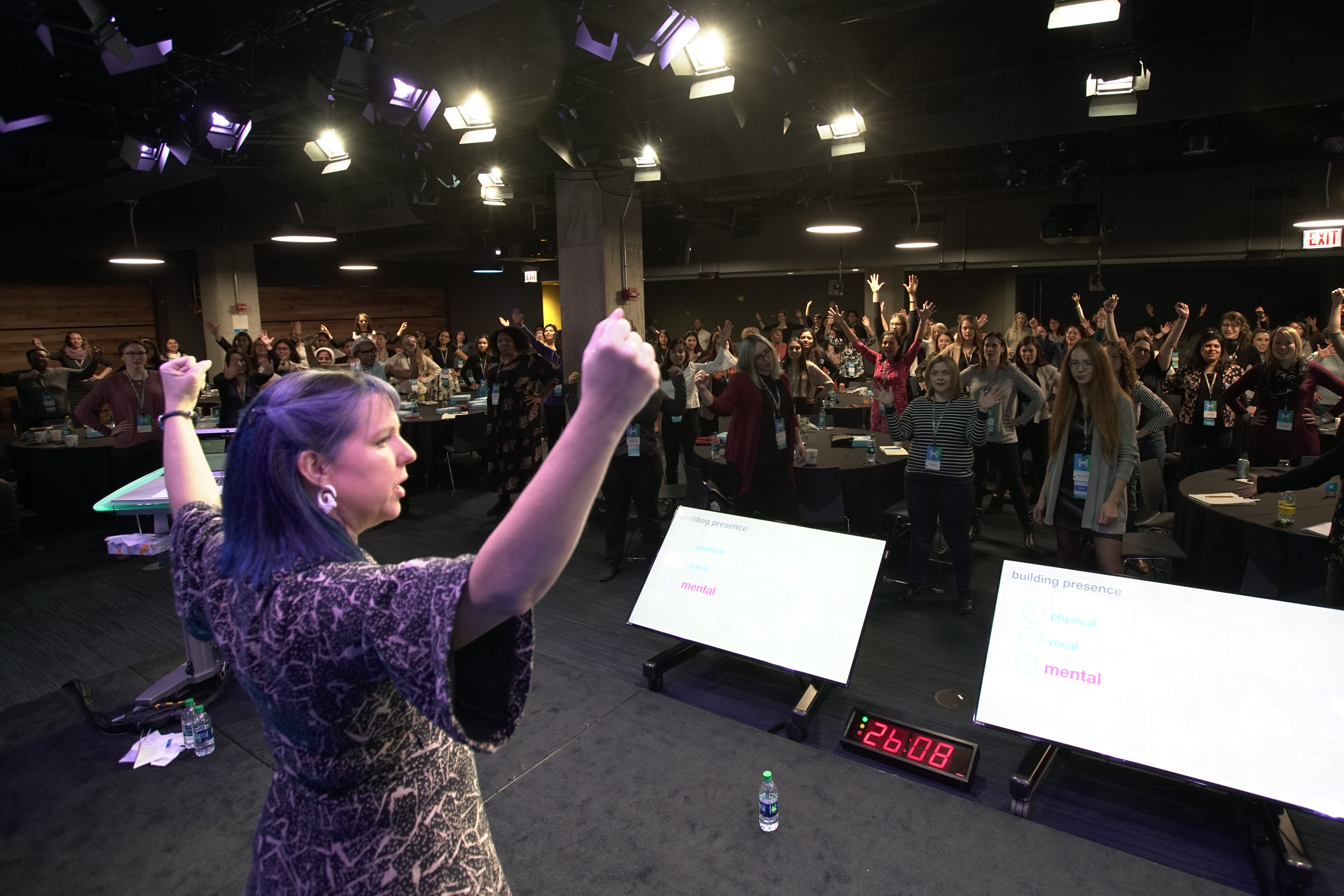 Kimberly on stage in Chicago leading a power pose to hundreds of women, non-binary, and trans entrepreneurs. 