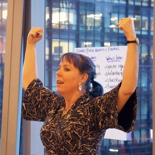 Kimberly MacLean coaching a room of non-profit leaders in executive presence and sharing their message. Kimberly is striking a power pose